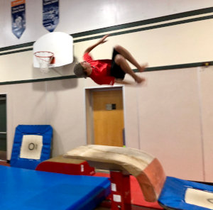 Young boy doing a back flip in parkour class.